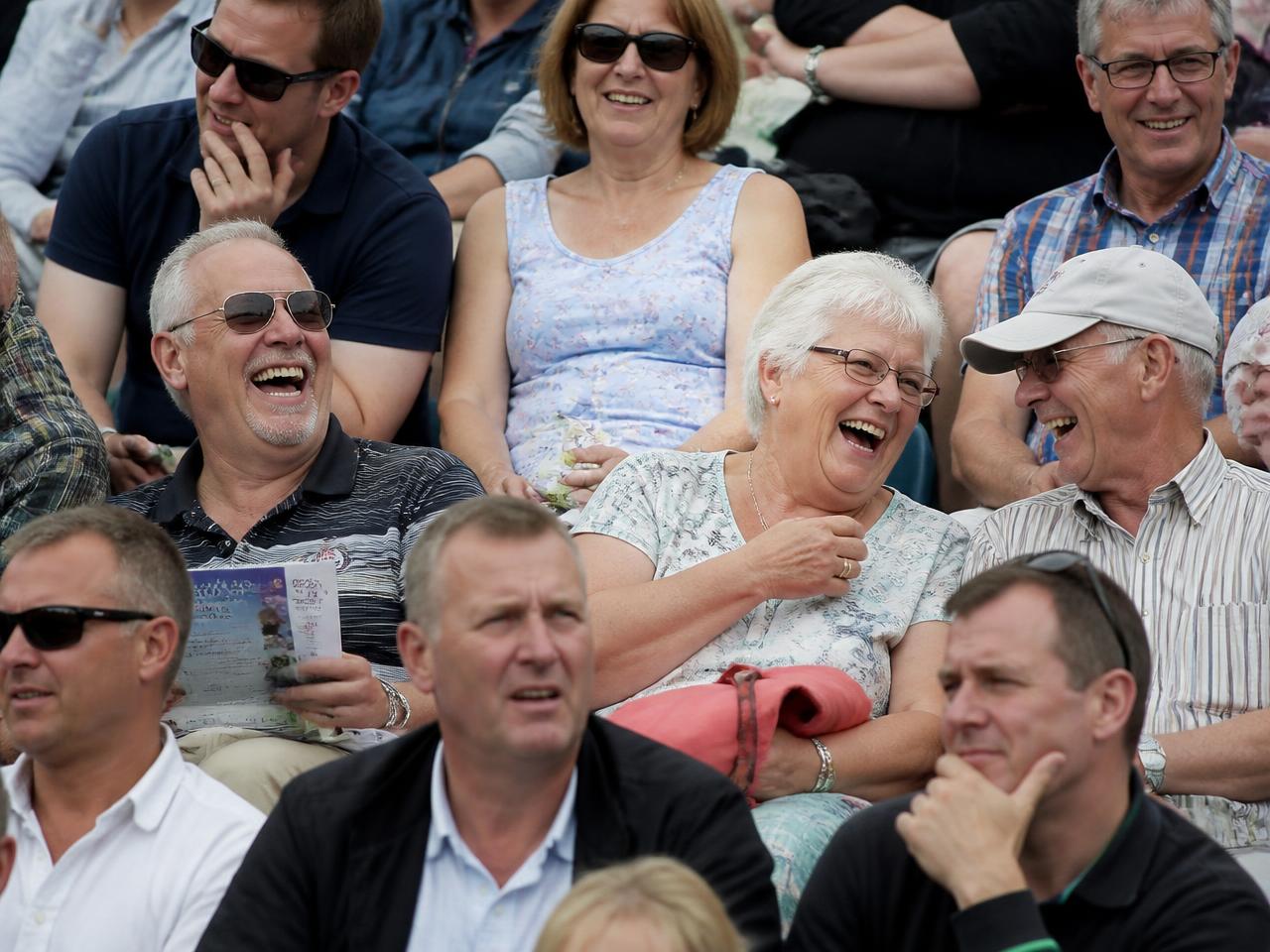 Spectators laughing in covered tiered seating at a UK showground