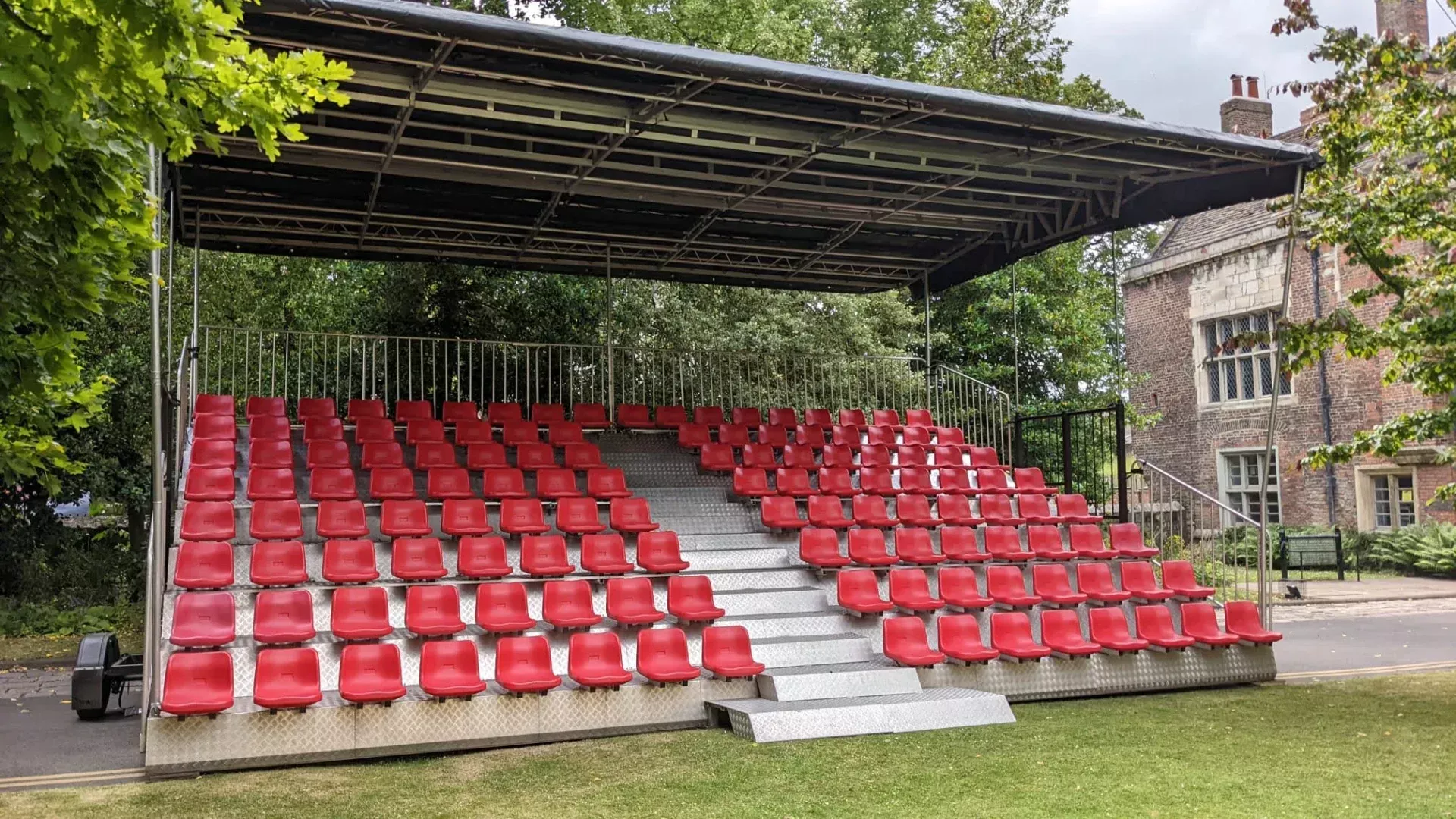 KL Seating GS130 mobile grandstand — 130 covered seats of red tiered seating, built beside a country house