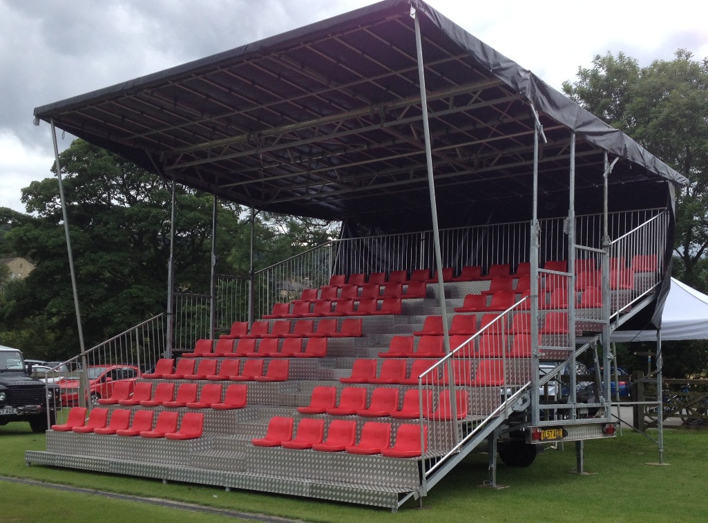 KL Seating GS90 mobile grandstand — 90 covered seats of temporary tiered seating, red seats and towing hitch, built on grass